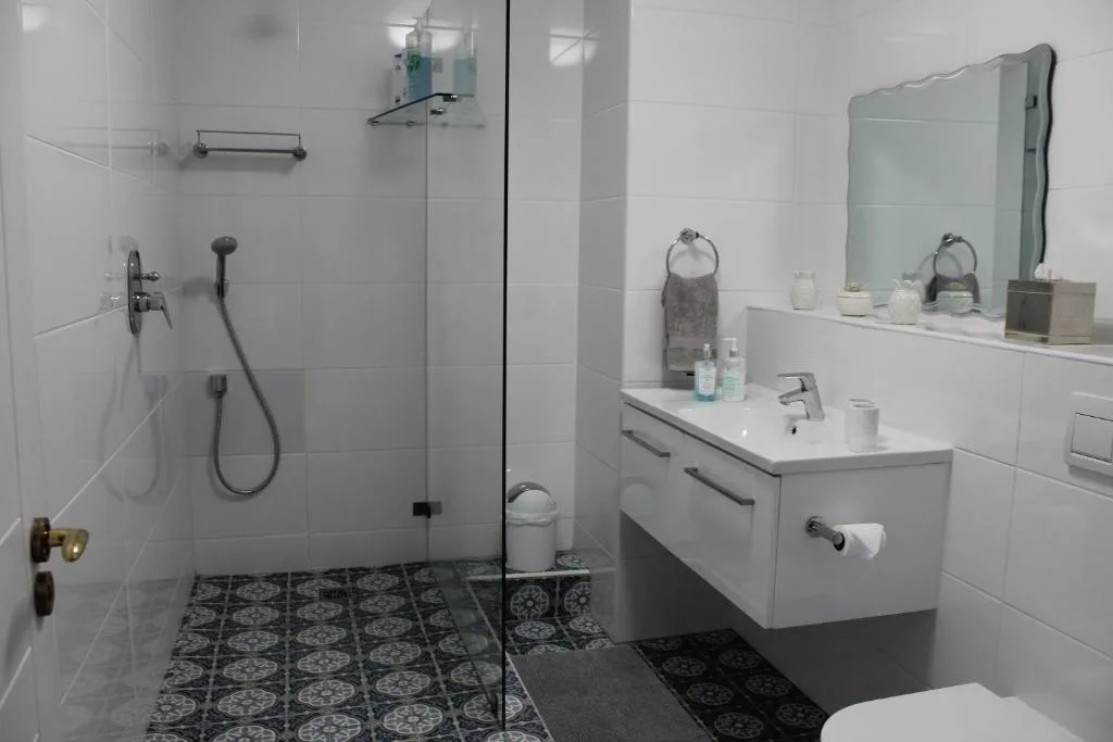 Modern bathroom with walk-in shower, white vanity, and patterned floor tiles