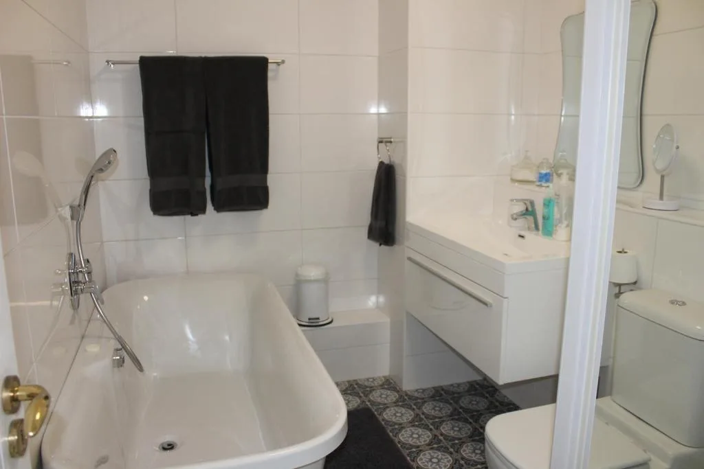 Modern bathroom with curved freestanding bathtub, white vanity, and toilet
