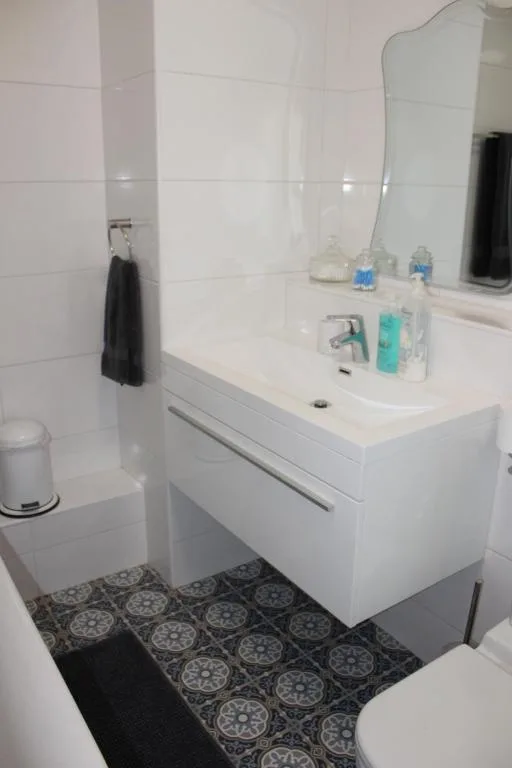 Modern white bathroom with vanity sink, mirror, and patterned floor tiles
