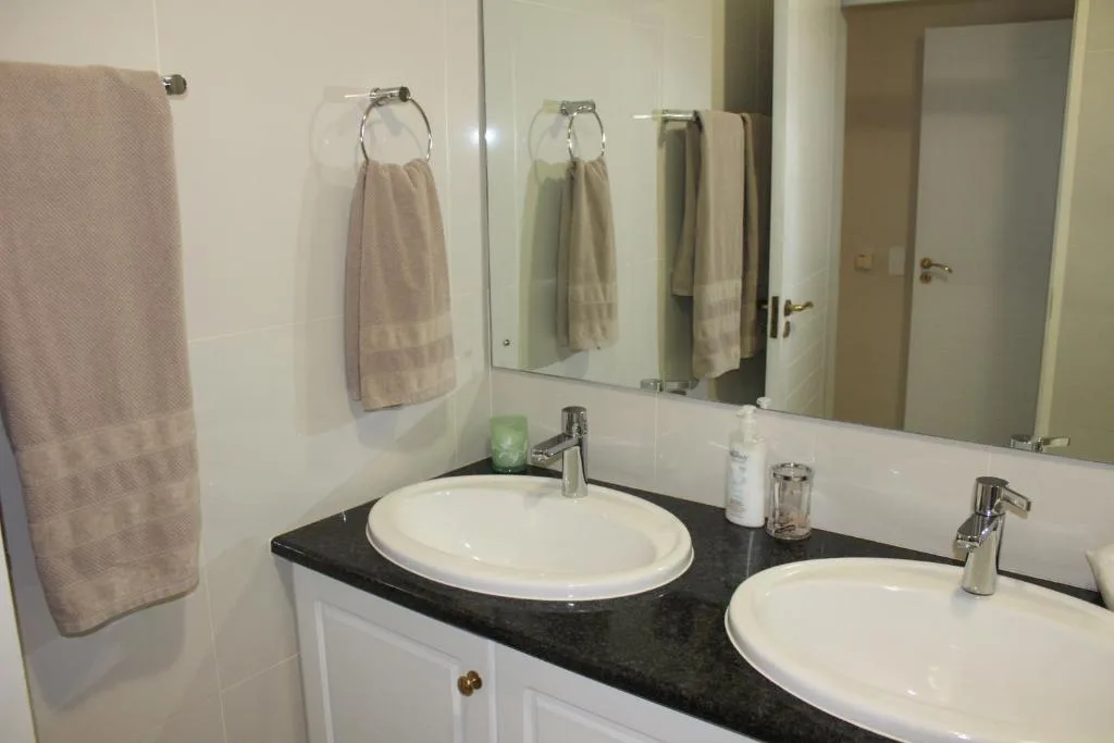 Double vanity bathroom with white sinks, black countertop, and mirrors