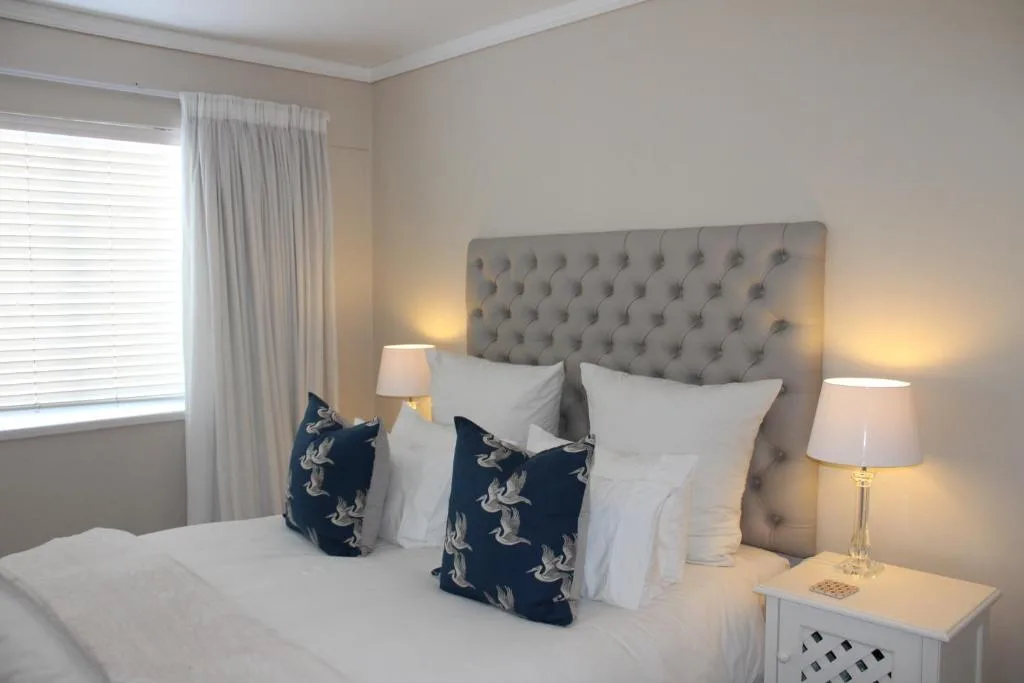 Spacious bedroom with tufted headboard, white linens, and bedside lamps