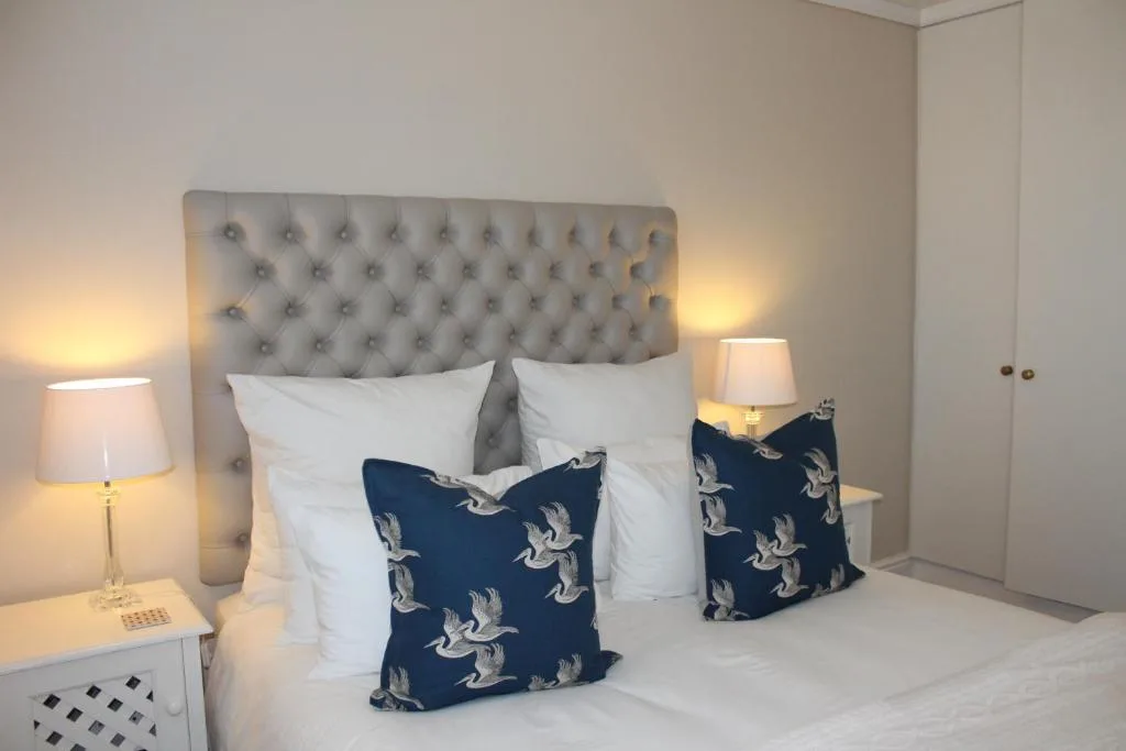 Modern bedroom with elegant tufted headboard, white pillows, and navy patterned cushions