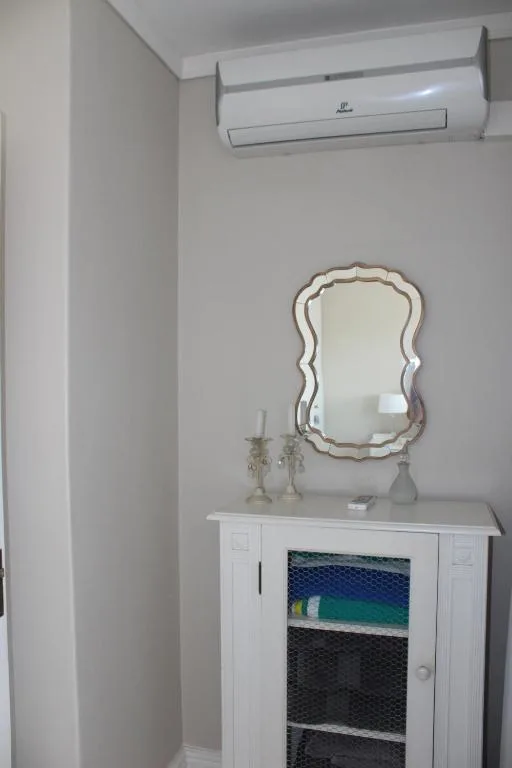 Bedroom corner with decorative mirror, air conditioning unit mounted above