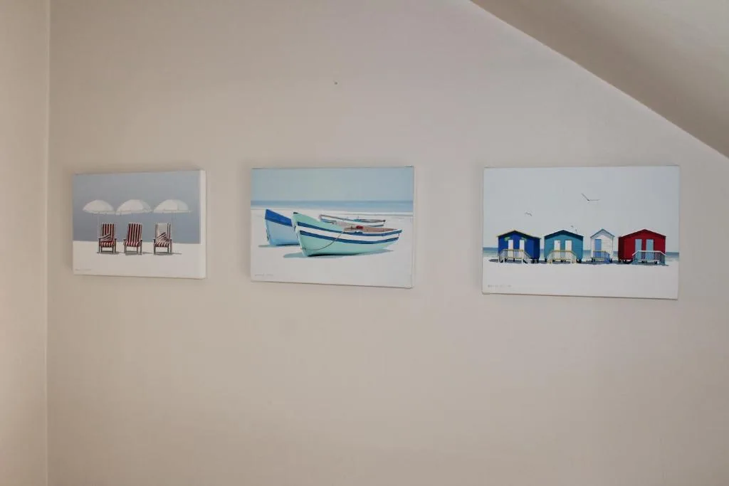 Three coastal-themed framed prints hanging on white bedroom wall