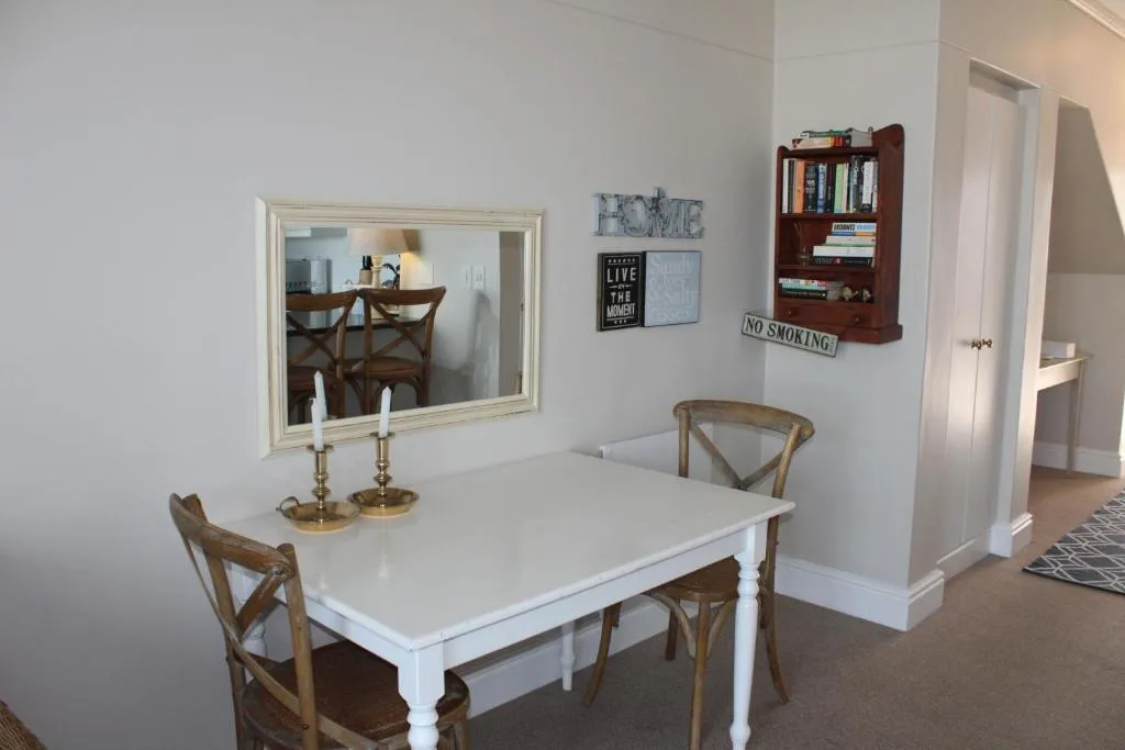 Bright dining room with white table, wooden chairs, and decorative wall mirror