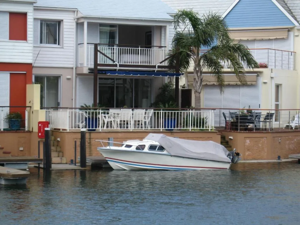 Waterfront apartment building with deck overlooking moored boat and lagoon