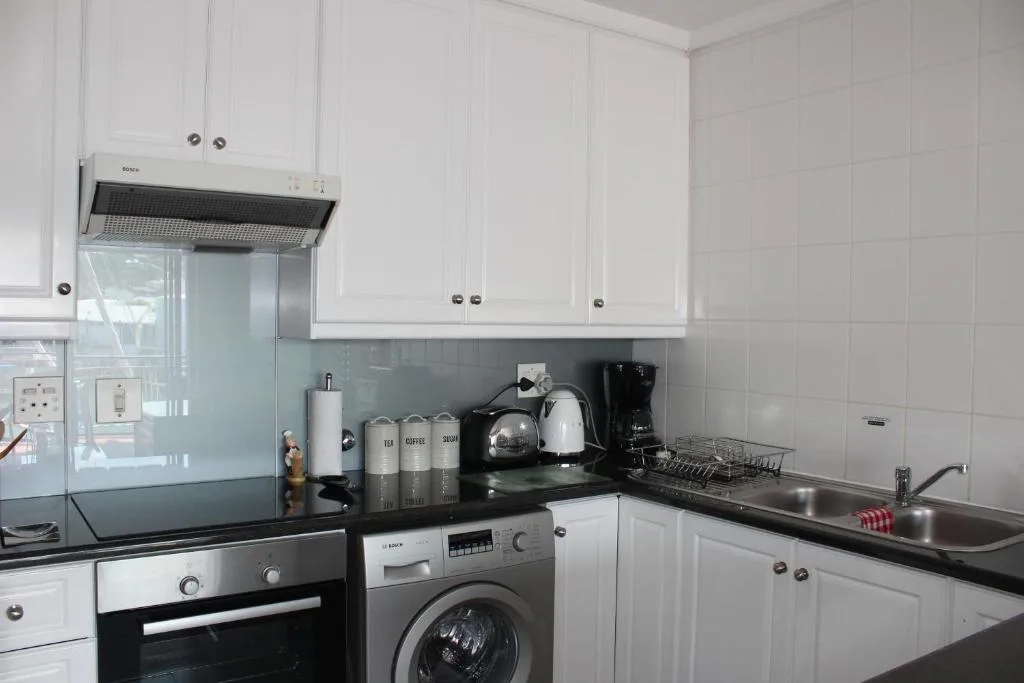 Modern kitchen with white cabinetry, black countertops, and stainless steel appliances