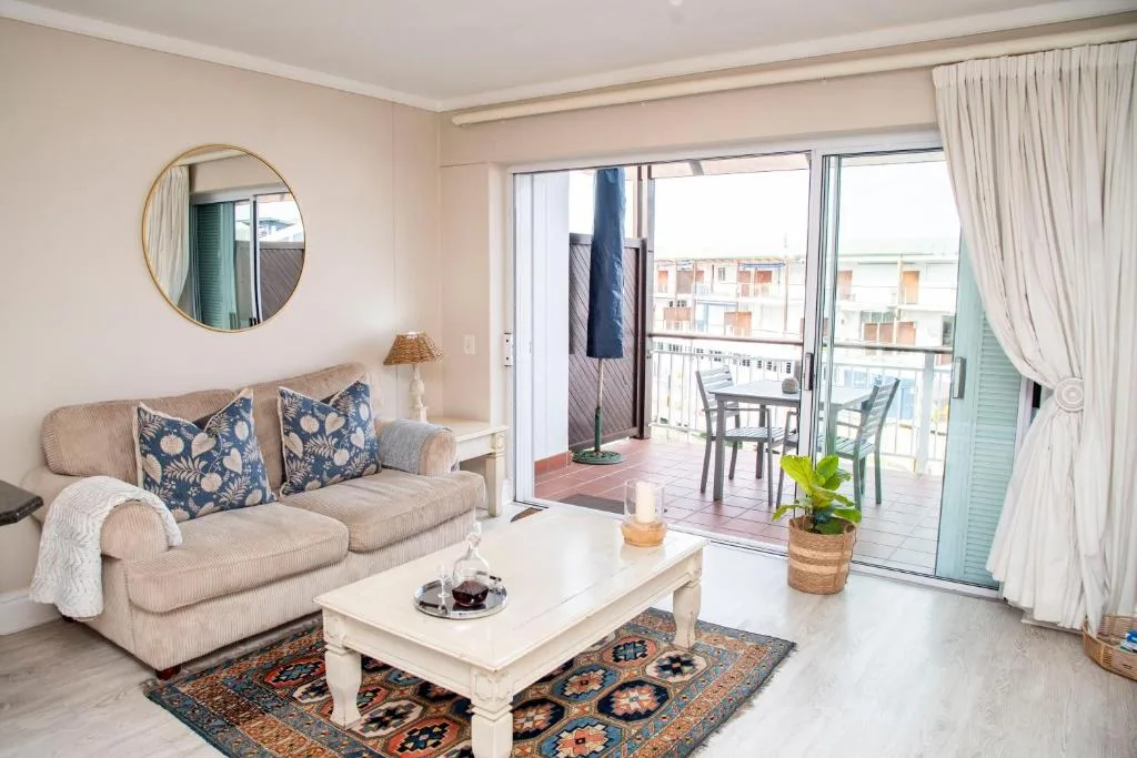 Bright lounge with cream sofa, coffee table, and access to balcony overlooking Knysna