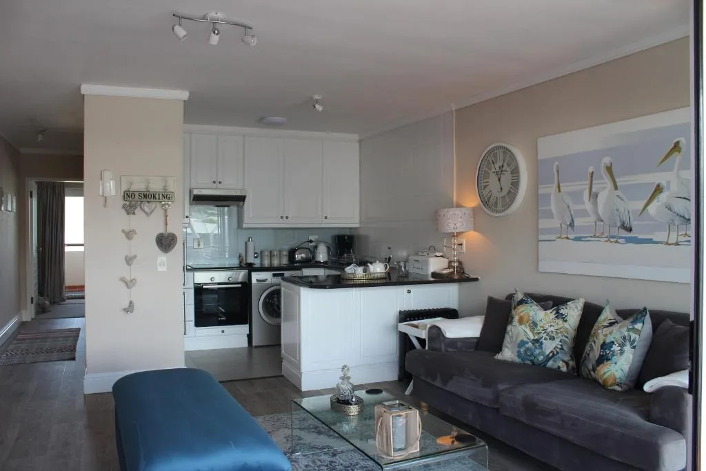Open-plan lounge with black sofa, blue chair, and integrated kitchen area