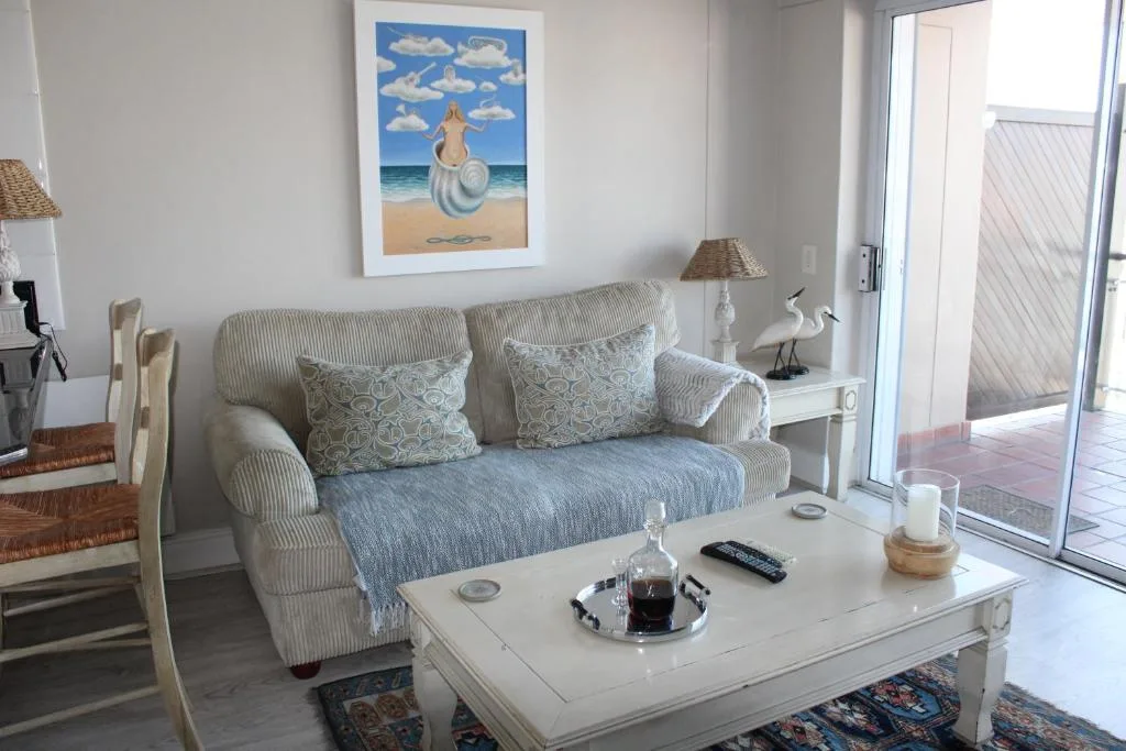 Bright lounge with striped sofa, white coffee table, and beach artwork
