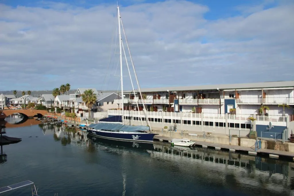 Waterfront view of moored sailboat and Knysna Quays apartment buildings