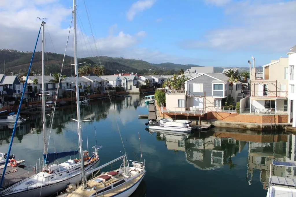 Scenic waterfront view of Knysna lagoon with sailboats and colorful houses