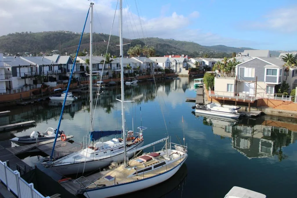 Scenic waterfront view of Knysna lagoon with sailboats and hillside backdrop