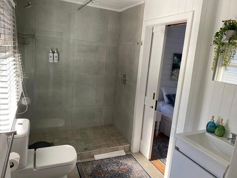 Modern bathroom with walk-in shower, white vanity, and toilet