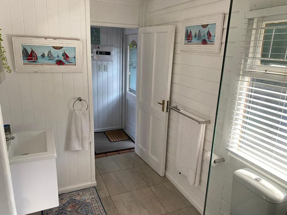 Bright white bathroom with tile flooring, vanity sink, and glass shower enclosure