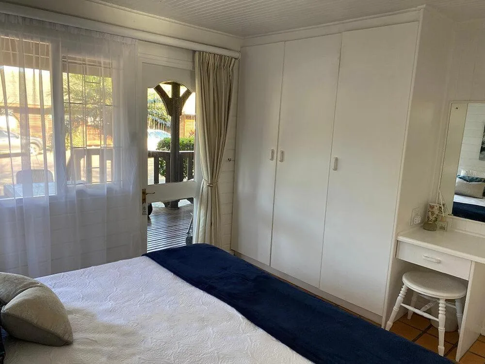 Bright bedroom with queen bed, built-in wardrobes, and deck access