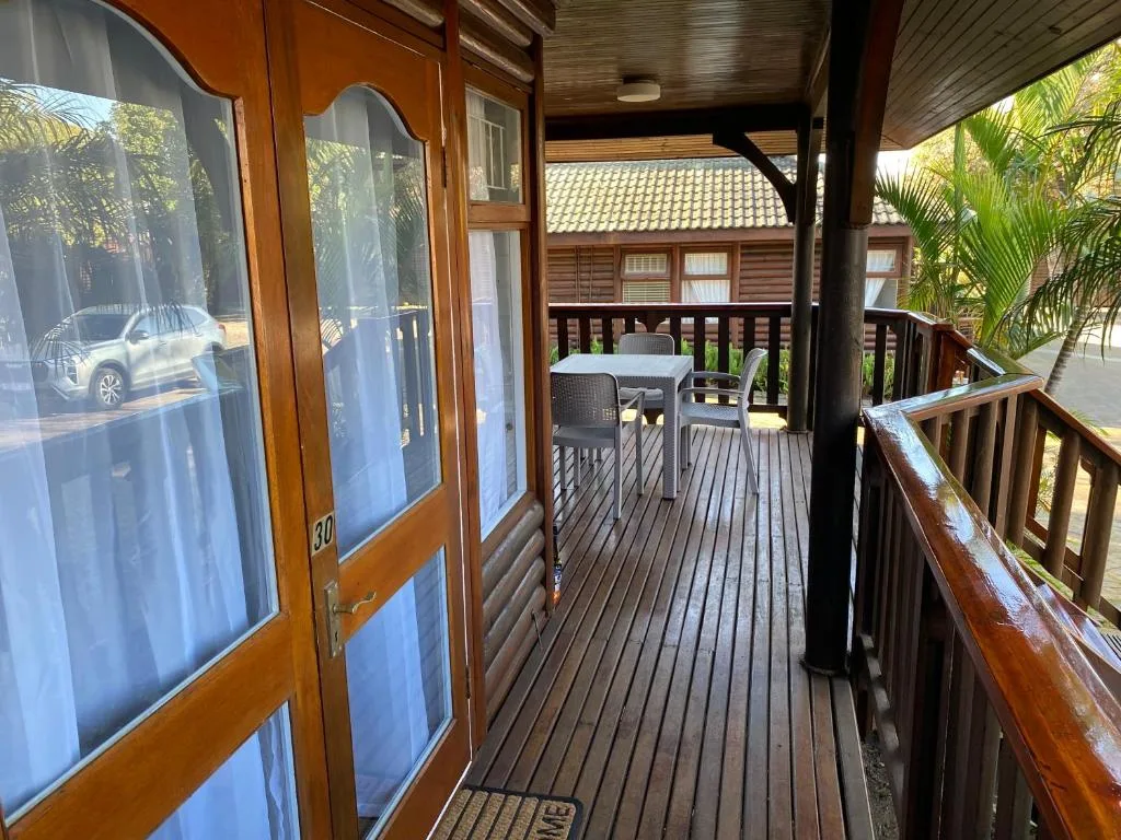 Wooden deck with dining table and dark wooden railings overlooking property