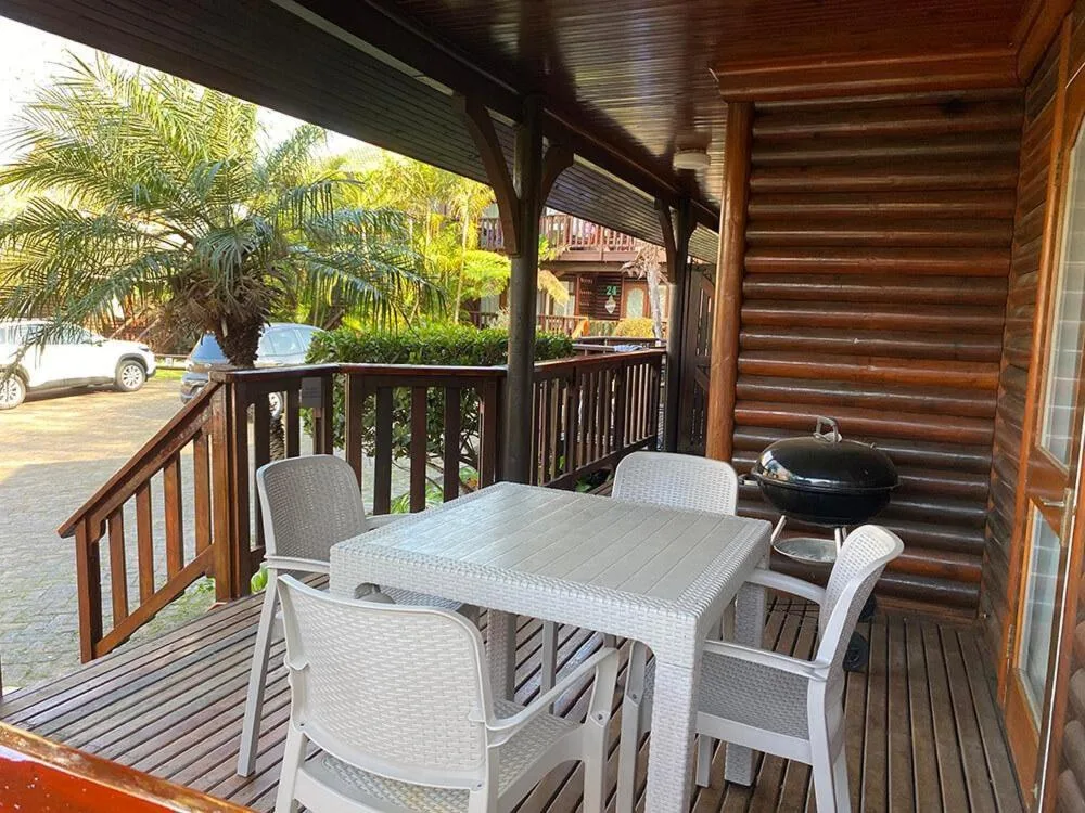 Covered wooden deck with dining table, chairs, and braai grill