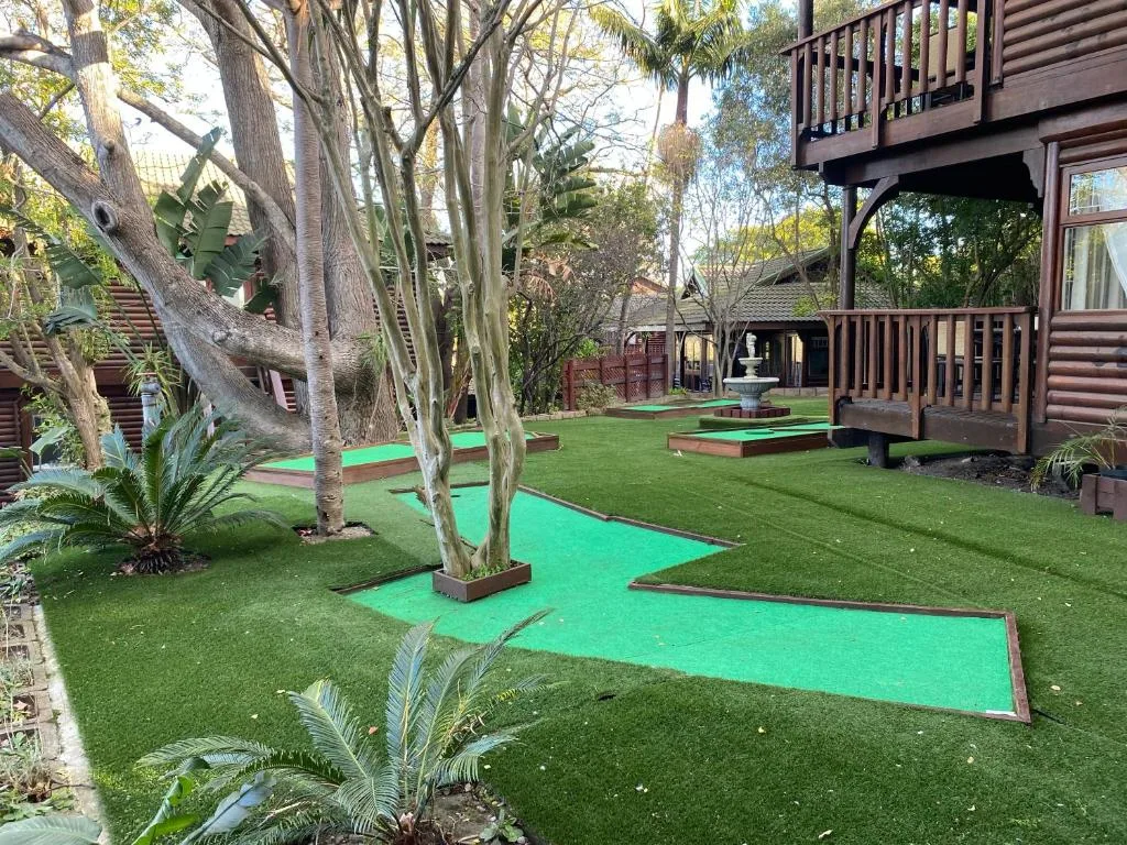 Mini golf course on manicured lawn with mature trees and wooden buildings
