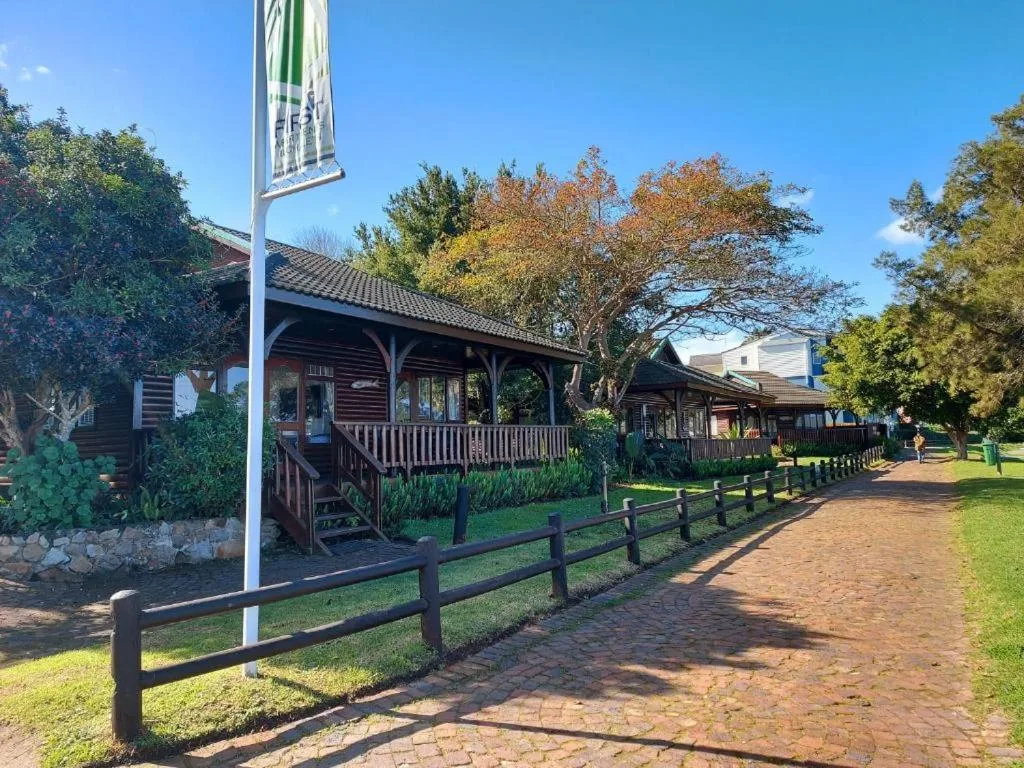 Rustic wooden buildings with covered porches and black fencing along brick pathway