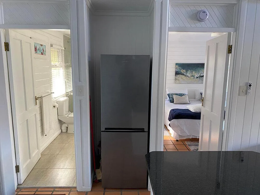 Modern kitchen hallway with black refrigerator and access to bathroom and bedroom
