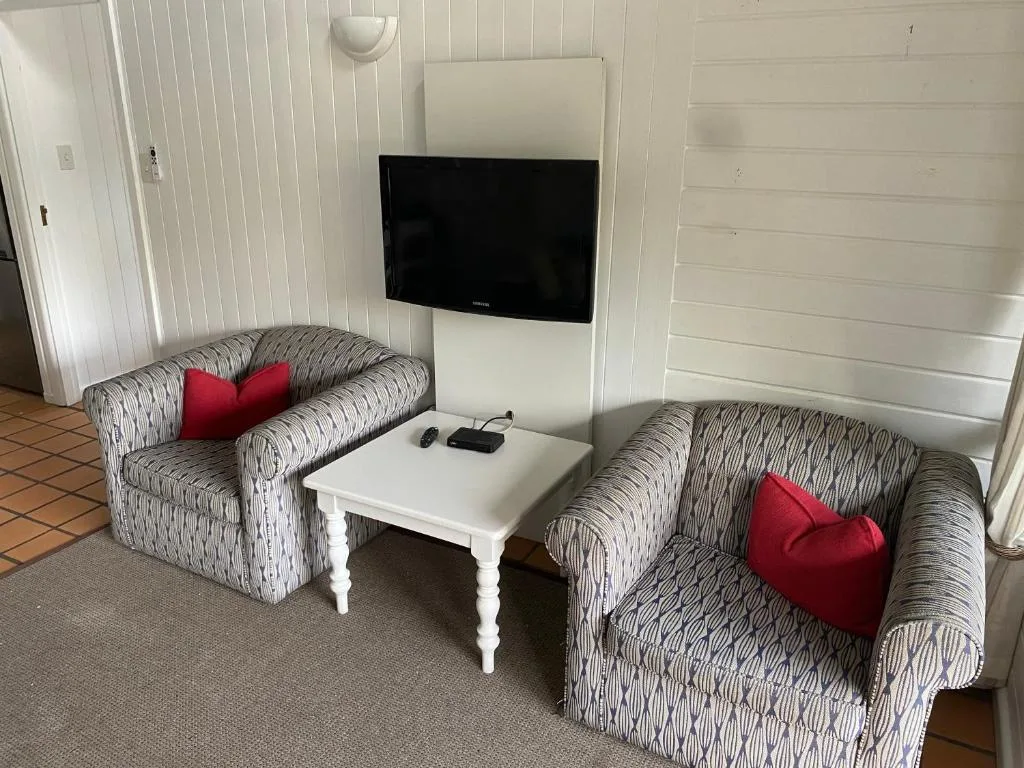 Bright lounge with patterned armchairs, wall-mounted TV, and white paneling