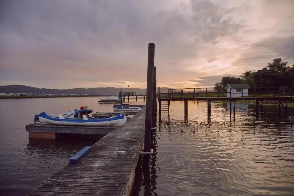 Serene Knysna lagoon at sunset with moored boats and wooden jetties