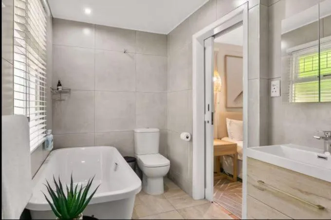 Modern bathroom with freestanding tub, toilet, and wooden vanity sink