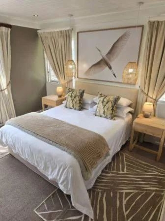 Luxury bedroom with king bed, neutral décor, pendant lighting, and artwork