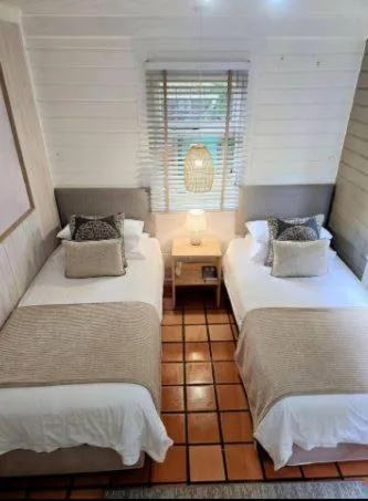 Twin bedroom with white bedding, decorative pillows, and natural light