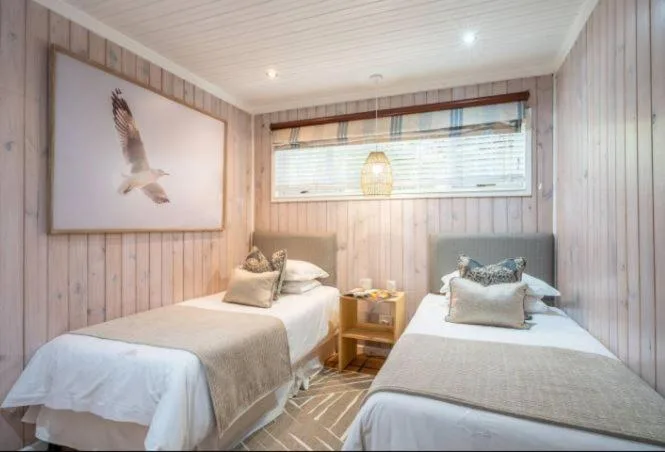 Twin bedroom with wooden walls, two single beds, and natural light from window