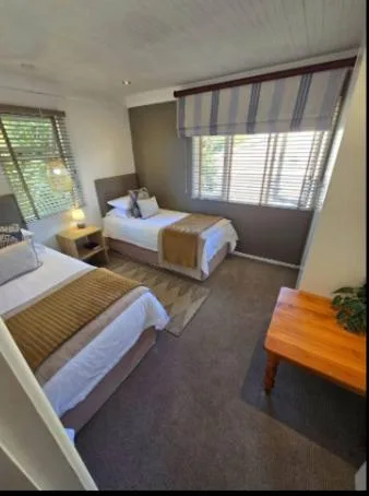 Spacious bedroom with two single beds and large windows overlooking garden