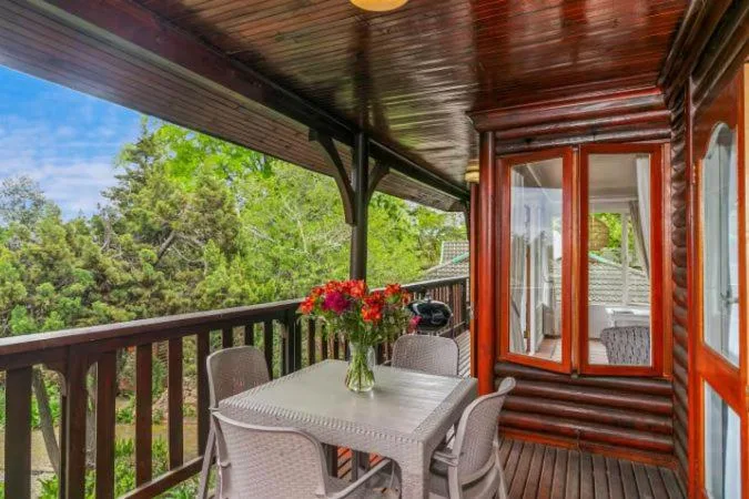 Covered deck with dining table overlooking lush green forest landscape
