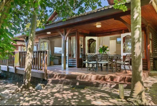 Shaded wooden deck with dining furniture and water views, tree-lined setting