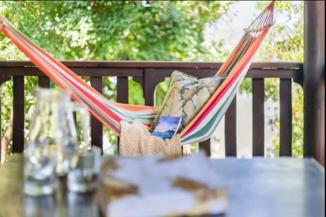 Colorful hammock on wooden deck surrounded by lush green foliage