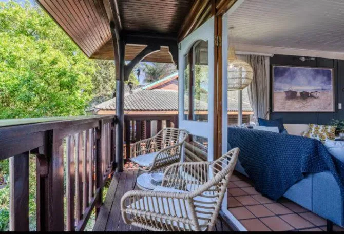 Covered deck with wicker chairs overlooking lush garden and water