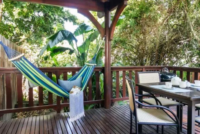 Shaded deck with hammock, table, and lush tropical vegetation surrounding
