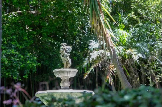 Ornamental stone fountain surrounded by lush tropical garden vegetation
