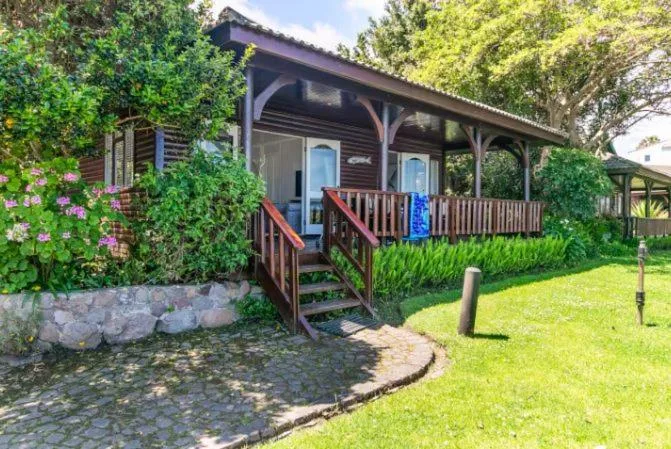 Charming wooden chalet with covered porch, green garden, and flowering vines