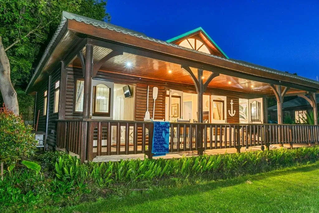 Illuminated luxury chalet with wraparound deck at twilight