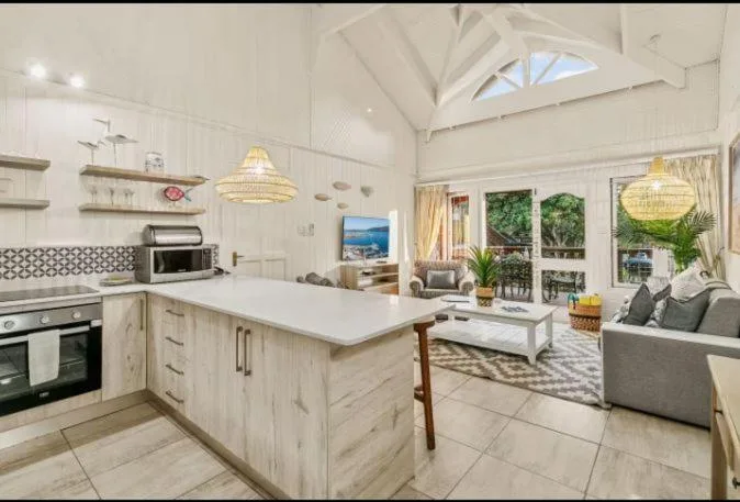 Modern open-plan kitchen with white cabinetry, island bench, and integrated lounge area