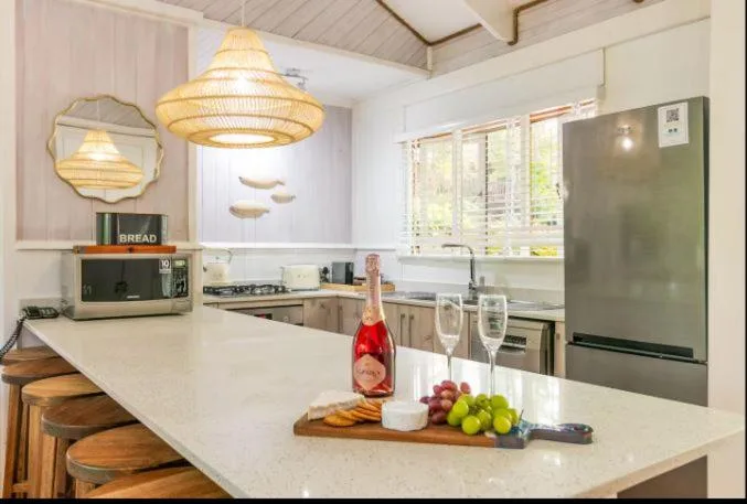 Modern kitchen with white countertops, rattan pendant lights, and stainless steel appliances