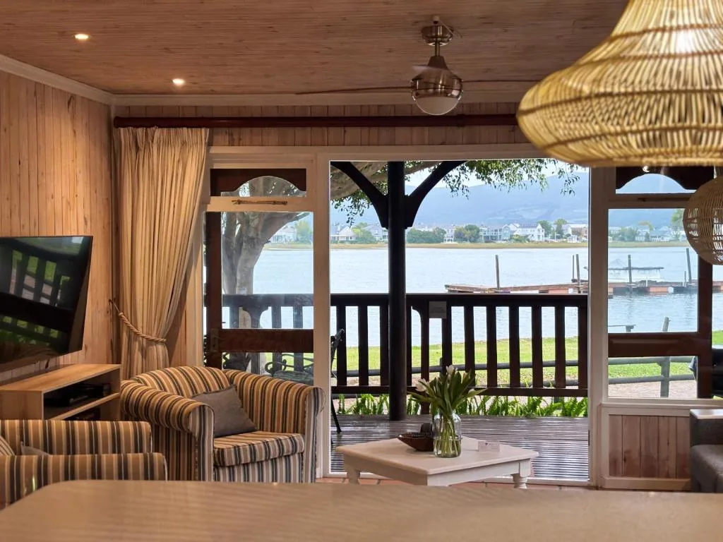 Waterfront lounge with striped armchairs overlooking Knysna lagoon and boats