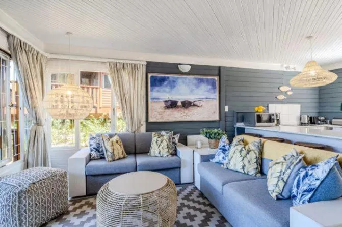 Spacious living room with blue sofas, wall-mounted TV, and ocean view