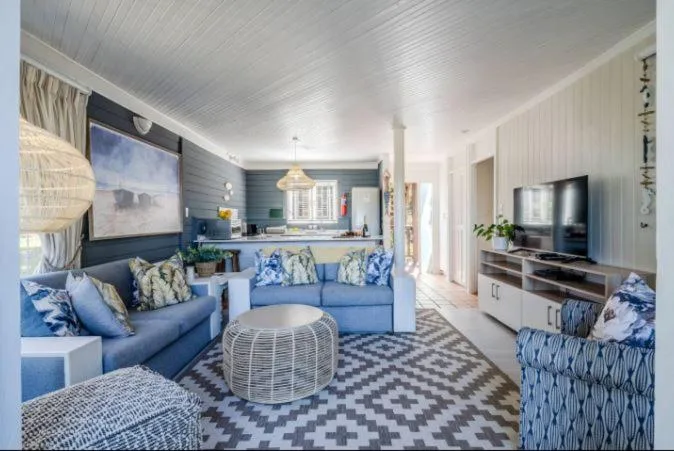 Bright modern lounge with blue sofa, television, and coastal decor