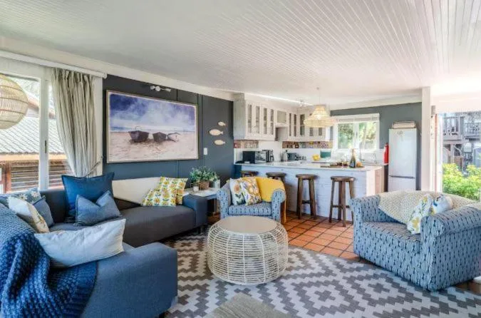 Open-plan living area with blue sofas, kitchen, and artwork on accent wall