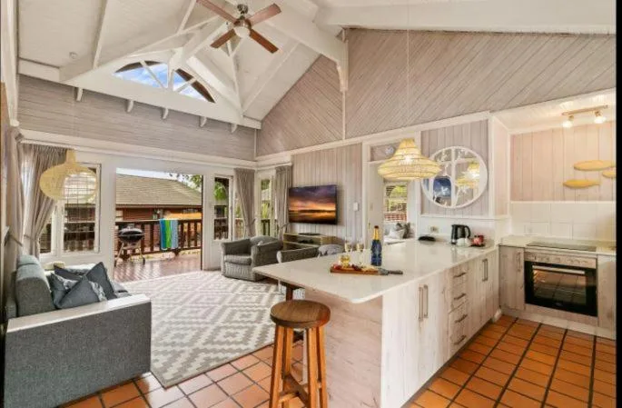 Open-plan living area with sofa, kitchen island, and vaulted ceiling