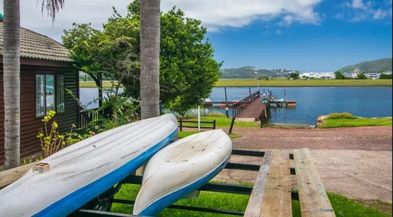 Waterfront property overlooks lagoon with boats, jetty, and distant mountains