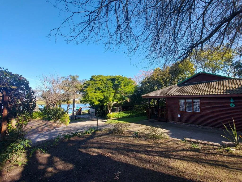 Red-brick building with tile roof surrounded by mature trees and garden pathways