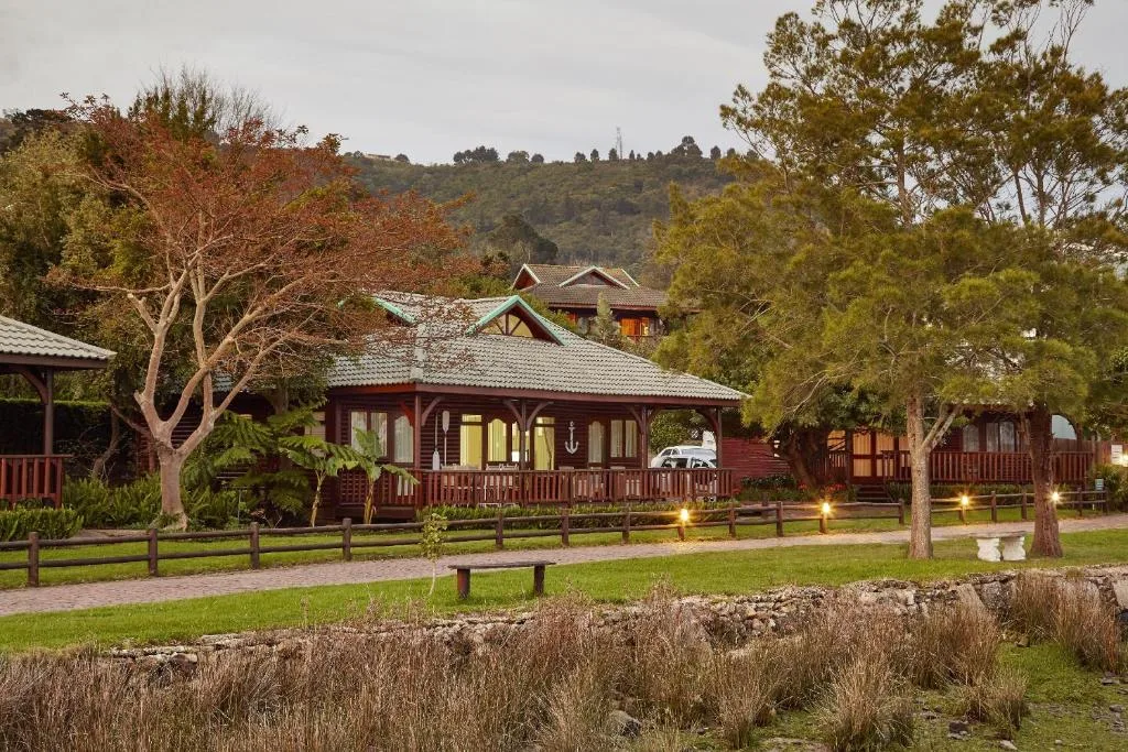 Red-roofed lodge with deck and railing surrounded by mature trees